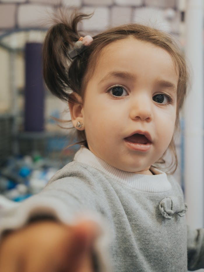 Mastering the First Impression: Your intriguing post title goes here Cute toddler in a cozy sweater reaching towards camera with a playful expression indoors.