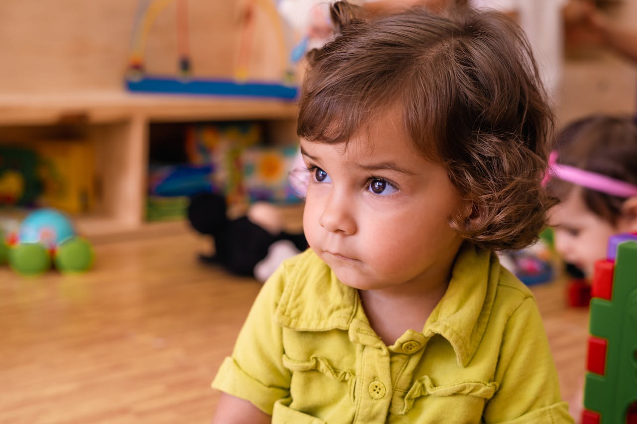 The Art of Drawing Readers In: Your attractive post title goes here Charming toddler with curly hair in a vibrant playroom, focusing on toys.