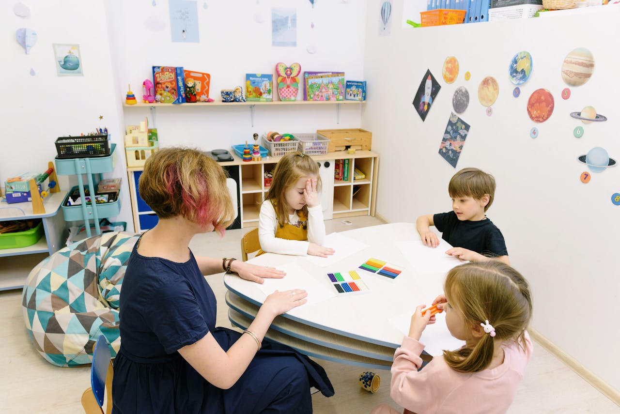 gallery-3 Children engage in a colorful activity with a teacher in a bright kindergarten classroom.