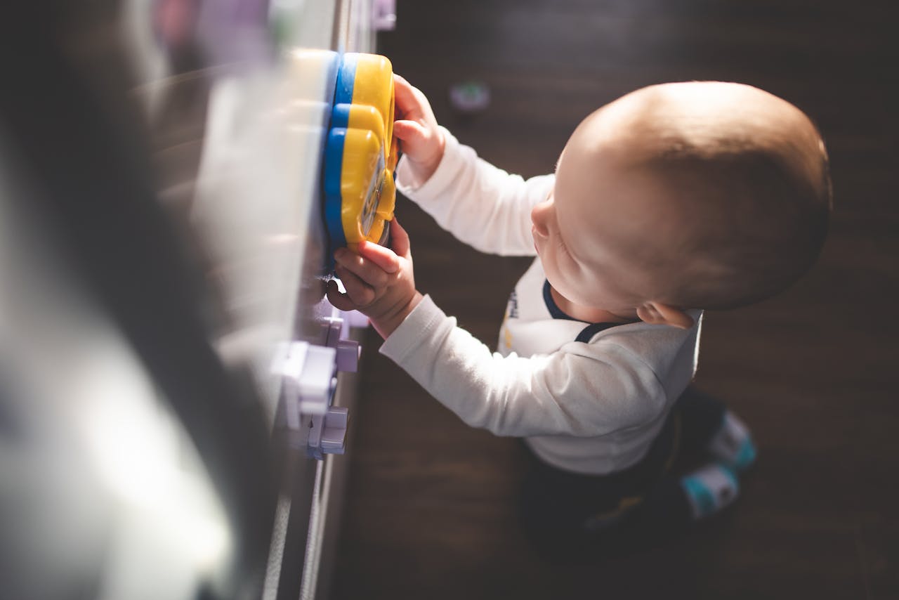 A cute toddler focusing intently while playing with a colorful toy indoors.